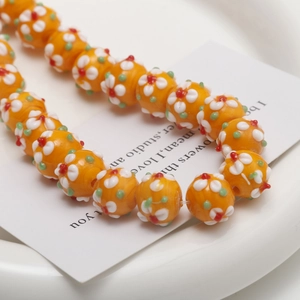 Detailed close-up of handmade orange floral glass beads for DIY jewelry making