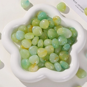 Macro detail of translucent light green and yellow acrylic stones in a white petal tray