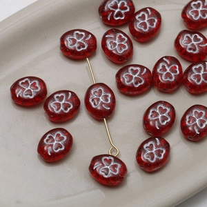 Macro view of red oval Czech glass beads with white clover pattern for DIY jewelry