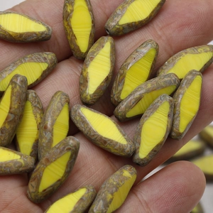 Hand holding yellow marble texture oval Czech glass beads for DIY jewelry making