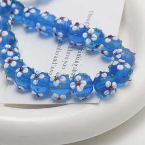 Detailed view of handmade blue glass beads with floral patterns for DIY jewelry crafting