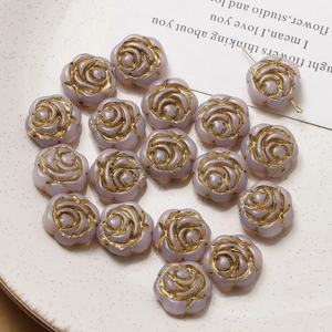 Detailed view of light purple gradient rose glass beads with gold-rimmed edges on a plate