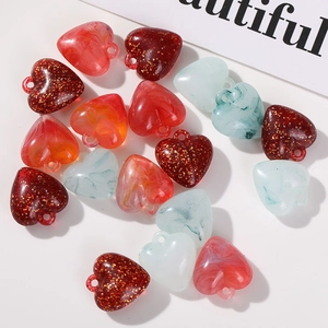 Macro shot of colorful acrylic heart beads with marble textures and gold glitter for DIY