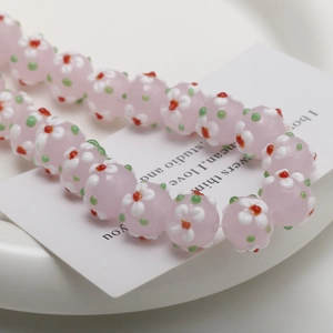 Macro view of light pink glass flower beads for DIY jewelry on white ceramic tray