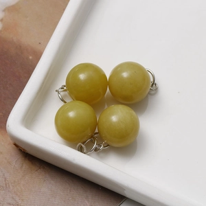 Macro shot of four 12mm round polished yellowish-green natural stone pendant charms