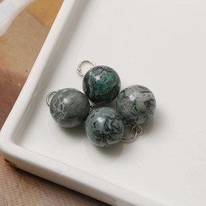 Macro detail of 12mm natural stone pendants with silver rings on a white tray