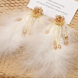 Detail of bohemian white feather earrings with crystal flower stud and beaded tassels