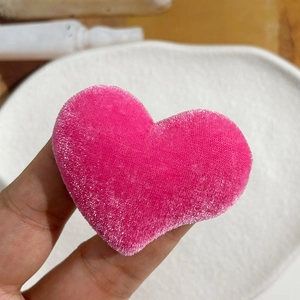Close-up of a soft pink velvet heart-shaped DIY accessory held in hand for scale
