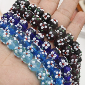 Handheld view of assorted Millefiori glass beads with white flower patterns for DIY jewelry