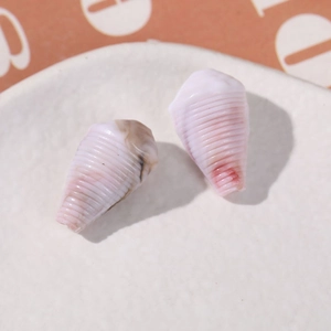 Macro detail of spiral conch-shaped acrylic beads with pink and white marbled texture