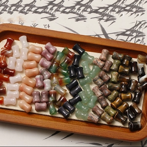 Macro shot of bamboo-shaped agate and quartz beads arranged in a wooden tray