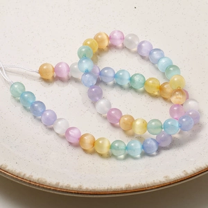Vue macro de perles œil de chat arc-en-ciel de 8mm pour bijoux DIY sur une assiette blanche