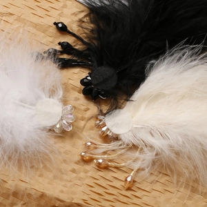 Detailed close-up of handmade feather hair clips with intricate beaded flower tassels