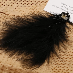 Detailed macro shot of vintage black feather earrings with beaded flower and crystal accents