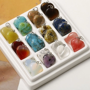 Macro shot of 12 varieties of heart-shaped gemstone pendants in a white display tray