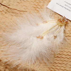 Macro view of beige feather accessory with amber crystal beads and tassel detail