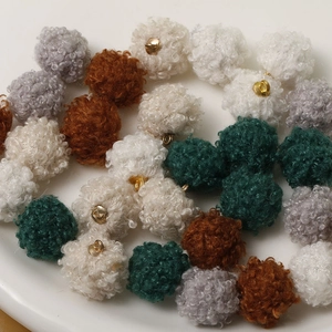 Close-up of colorful faux fur pom-poms with gold metal rings for DIY jewelry making