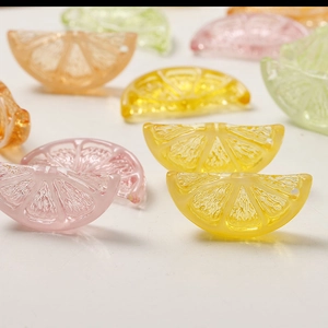 Macro shot of colorful resin citrus slice charms for DIY jewelry making on white background