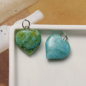 Macro detail of heart-shaped natural stone pendants with silver jump rings for DIY jewelry