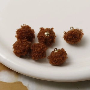 Detailed view of brown plush faux fur balls with golden metal rings for DIY jewelry making