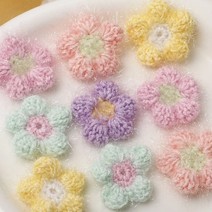 Makroaufnahme flauschiger Häkelblumen in Pastellfarben für DIY-Haarschmuck und Basteln