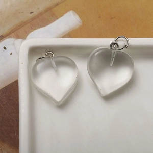 Macro shot of two transparent heart-shaped crystal pendants with silver metal loops