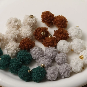 Close-up of lamb wool plush ball pendants with gold metal rings for DIY jewelry crafting