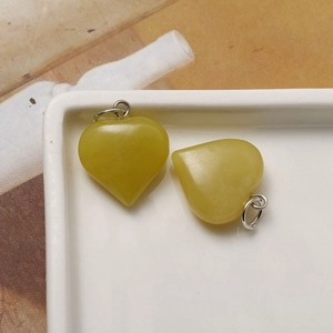 Macro shot of yellow natural stone heart pendants on a white ceramic tray with metal rings