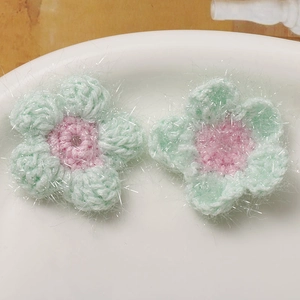 Detailaufnahme handgefertigter Häkelblumen mit Glitzergarn für DIY-Haarschmuckzubehör
