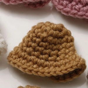 Macro shot of hand-knitted caramel miniature crochet hat for DIY crafts and doll accessories
