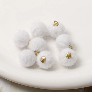 Nahaufnahme von acht weißen Kunstpelz-Pompons mit goldenen Ösen für DIY-Schmuckherstellung