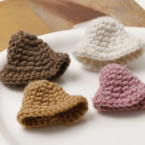 Detailed macro view of four miniature crochet hats in brown, camel, white and pink colors