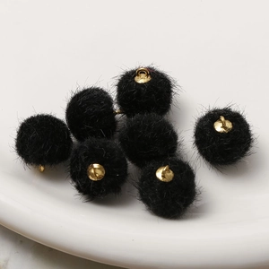 Makro-Detail von schwarzen Kunstpelz-Pompons mit goldenen Ösen für DIY-Schmuck