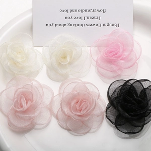 Detailed macro view of layered organza rose fabric flowers in pink, white, and black tones