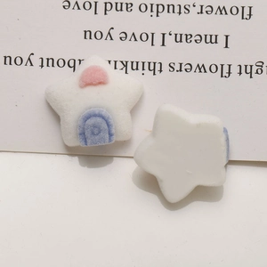 Macro shot of white flocked star-shaped DIY charms with pink heart and blue door details