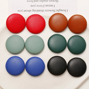 Flat lay of circular leather charms with lychee texture in assorted classic colors