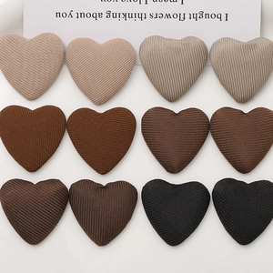 Flat lay of twelve heart-shaped fabric buttons in earthy gradient tones on a white base