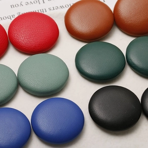 Macro shot of assorted round leather-covered buttons with textured litchi pattern