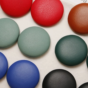 Close-up of assorted round leather-wrapped buttons with lychee grain texture details