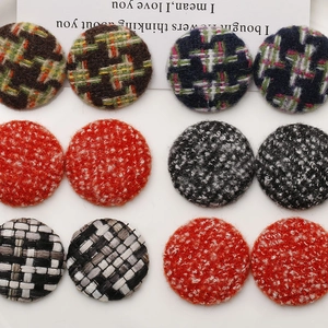 Macro shot of 12 round fabric-covered buttons in assorted tweed and twill textures