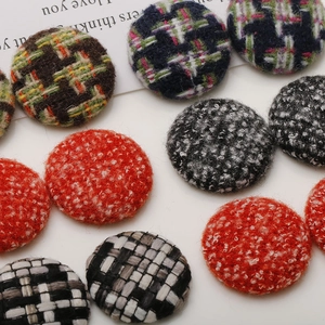 Detailed macro view of various tweed and fabric covered round buttons for DIY hair accessories