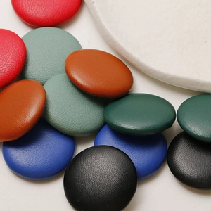 Detailed macro shot of assorted faux leather round buttons showing rich pebble grain textures