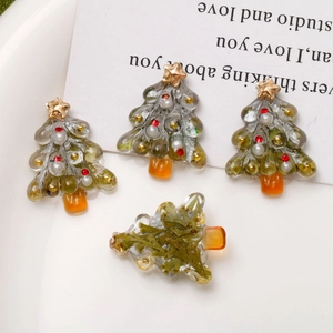 Detailed macro view of resin Christmas tree charms with gold foil and dried leaves