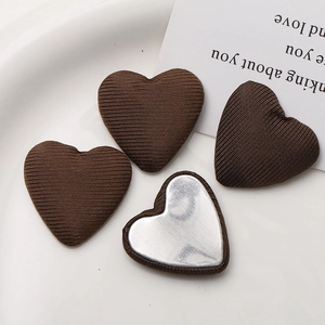 Close-up of heart-shaped fabric DIY buttons with brown striped texture and metal back