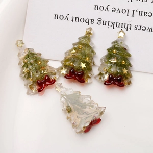 Detail view of resin Christmas tree pendants with gold foil and red bowknot accents