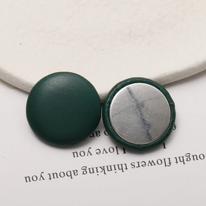 Detail of dark green lychee pattern leather round button with silver metal flat back