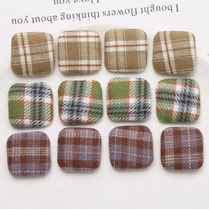 Macro detail of square fabric-wrapped buttons in vintage plaid for DIY earring crafts