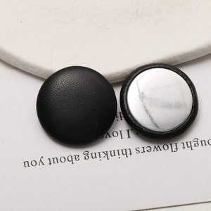 Close-up of black leather covered round buttons with silver metal back for DIY crafts