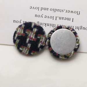 Close-up of houndstooth fabric buttons with smooth silver metal backing for DIY hair accessories