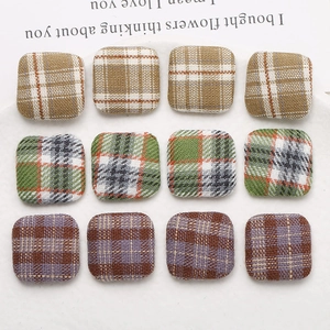 Macro detail of square plaid fabric buttons for DIY earrings in brown, green and purple